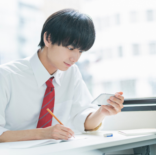 male student working at a table looking at a calculator