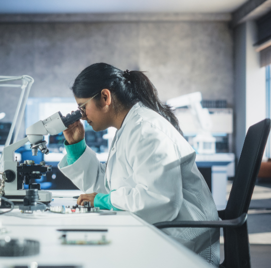 older female student looking through a microscope in a classroom