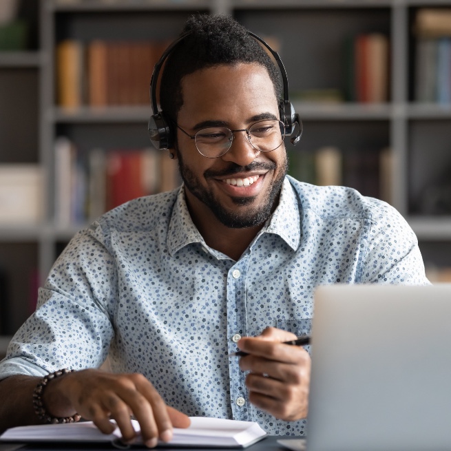 A cheerful male online tutor at work with his laptop